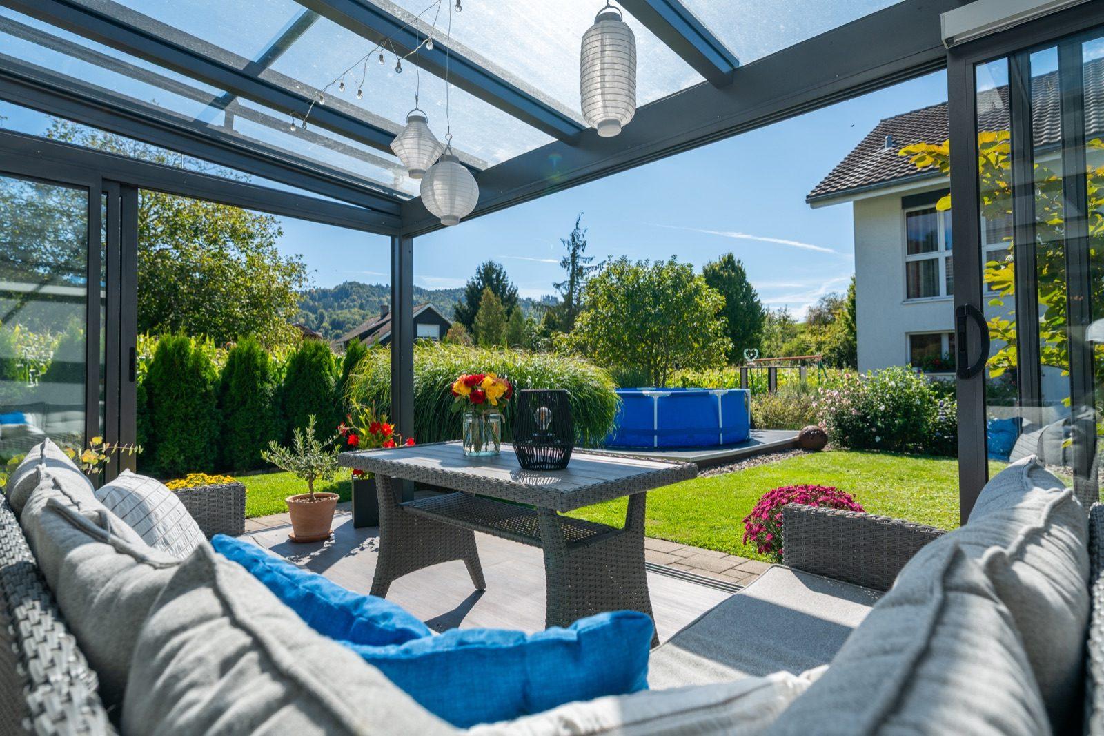 Überdachte Terrasse mit Sitzlandschaft und Blick in den Garten